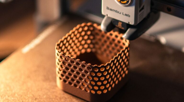 Close-up of a 3D printer creating a hexagonal object in a dimly lit workspace.